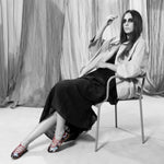 Modelo sentada con Bailarina II Fresa de defloresyfloreros, zapato plano bordado con lentejuelas multicolor y lazada rosa