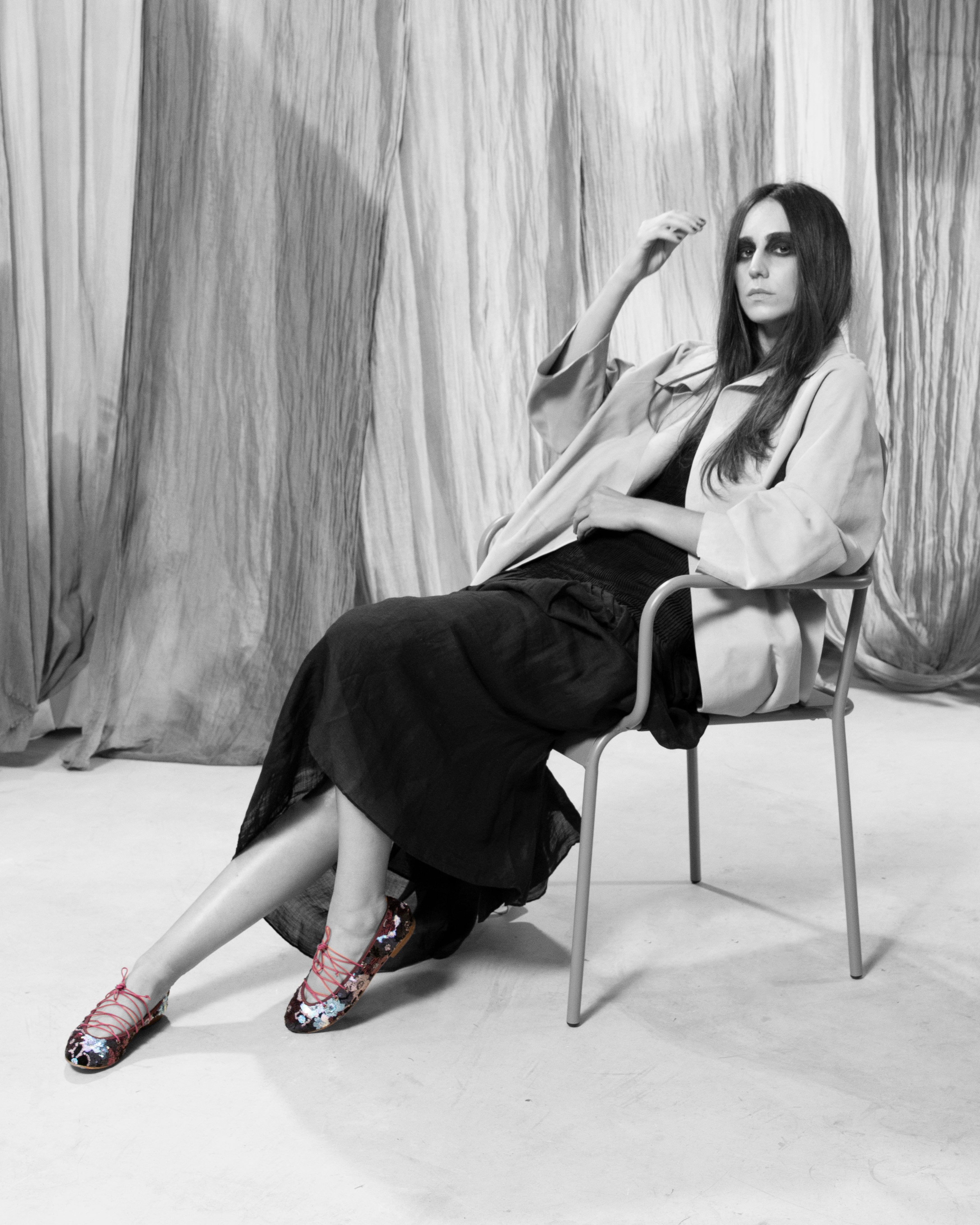 Modelo sentada con Bailarina II Fresa de defloresyfloreros, zapato plano bordado con lentejuelas multicolor y lazada rosa