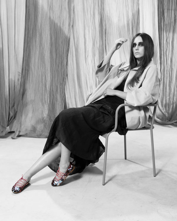 Modelo sentada con Bailarina II Fresa de defloresyfloreros, zapato plano bordado con lentejuelas multicolor y lazada rosa